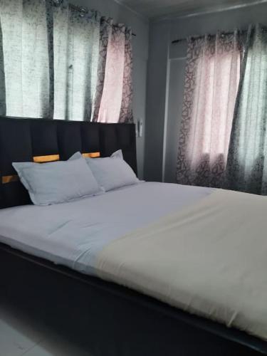 a bedroom with a white bed with two windows at The Alpha* residence in Tema