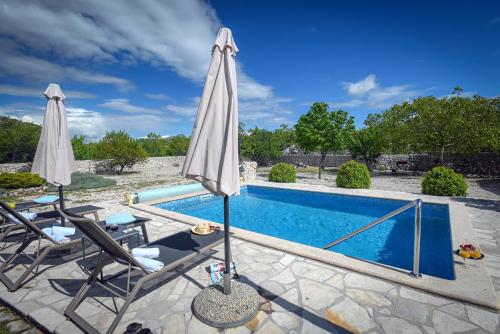 a pool with two umbrellas and two chairs next to a swimming pool at Villa Silentio, complete privacy near Makarska in Duge Njive