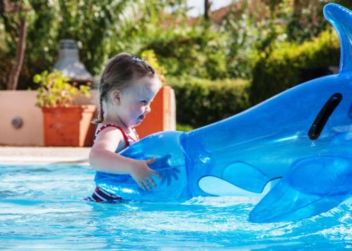 a little girl in the water playing with a blue inflatable whale at G George in Nydri