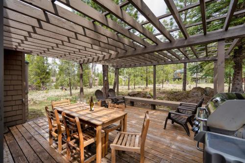 a wooden deck with a wooden table and chairs at Welcome to the Kinglet's Nest, Spacious property with AC SHARC, Hot-tub, Bikes, Games, Grill, Golf and Pets in Sunriver