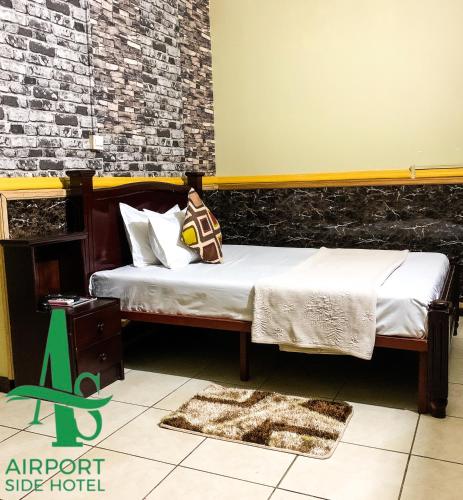 a bedroom with two beds and a brick wall at Airport Side Hotel in Accra