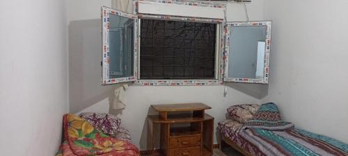 Habitación con ventana, cama y mesa. en Perle, en Aïn El Turk