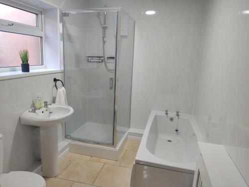 baño blanco con ducha y lavamanos en 3 Bedroom Entire House en Middlesbrough