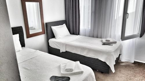a hotel room with two beds and a mirror at Merkez Kumsal Pansiyon in Bodrum City