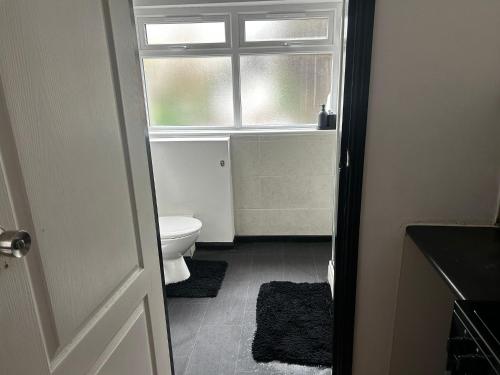 a bathroom with a toilet and a window at Kensington Stories - 4 Bed House in Watford