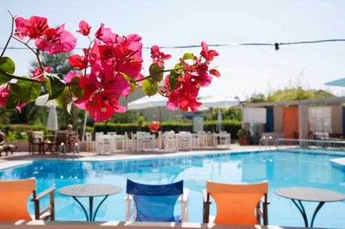 a pool with tables and chairs and pink flowers at G George in Nydri
