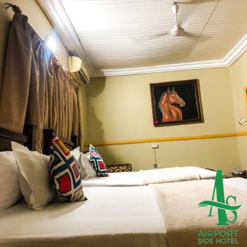two beds in a room with a picture of a horse on the wall at Airport Side Hotel in Accra