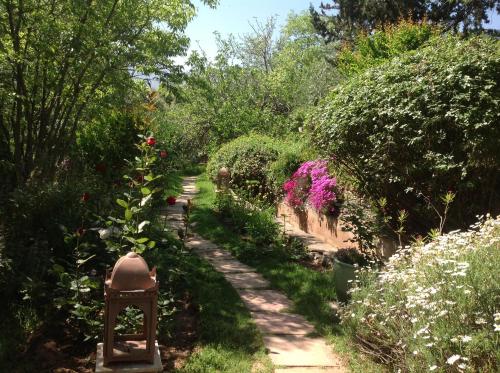 a path through a garden with flowers and plants at MAROC LODGE Atlas Mountain Retreat in Amizmiz