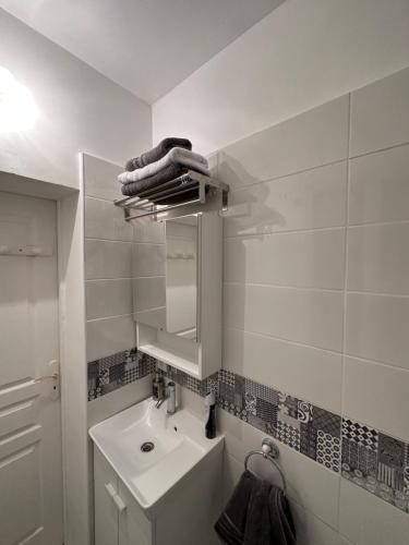 une salle de bain blanche avec un lavabo et un miroir dans l'établissement Un studio au sacré cœur Montmartre, à Paris
