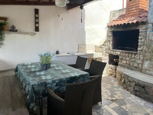 Un patio con mesa y sillas y una chimenea. en Libra, en Okrug Gornji