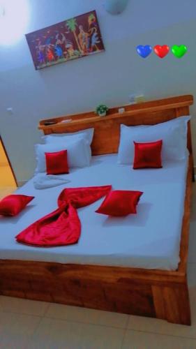 1 dormitorio con 1 cama con almohadas rojas en Résidences Hôtel Perle Bleue, en Cotonou