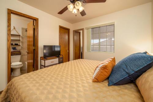 een slaapkamer met een bed, een plafondventilator en een televisie bij SPA! KING BED! BOAT parking! Villa w/ water views! in Lake Havasu City