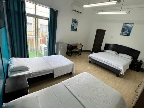 a bedroom with two beds and a table and a window at Perla Suites Malecón in Guayaquil