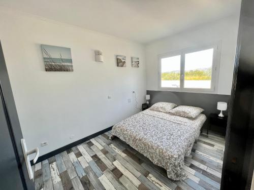 une chambre blanche avec un lit et une fenêtre dans l'établissement Maison de vacances à la plage, à Frontignan