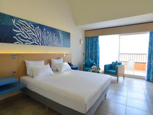 a hotel room with a large bed and a large window at Novotel Marsa Alam Beach Resort in Quseir