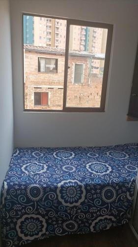 ein Schlafzimmer mit einem Bett und einem großen Fenster in der Unterkunft Habitacion 401,402,403,404 in Medellín