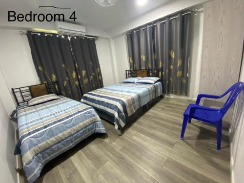 2 Betten und ein blauer Stuhl in einem Zimmer in der Unterkunft Drasa Homestay in Lautoka