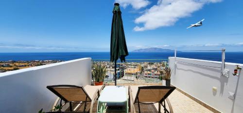 an umbrella and chairs on a balcony with a view of the ocean at Casinha Nova - Comfort & Class in Fogo in São Filipe