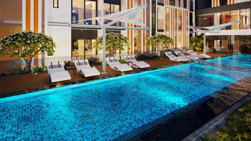 a large swimming pool with lounge chairs in a building at Studio Sofia Center in Ấp Rạch Mẹo