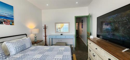 a bedroom with a large flat screen tv and a bed at Casinha Nova - Comfort & Class in Fogo in São Filipe