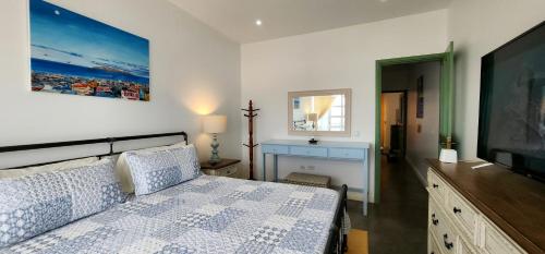 a bedroom with a bed and a flat screen tv at Casinha Nova - Comfort & Class in Fogo in São Filipe
