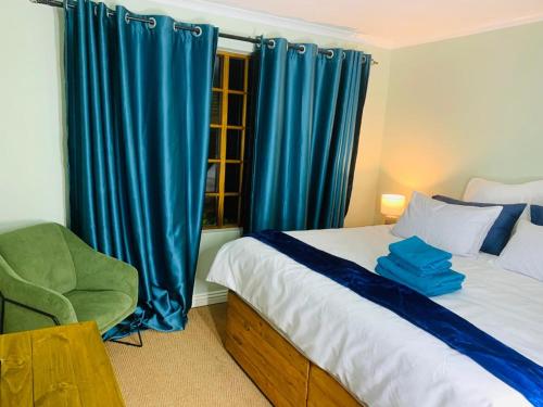 a bedroom with a bed with blue curtains and a chair at Afrikawisa@Rosebank in Johannesburg