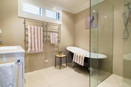 a bathroom with a tub and a sink and a shower at Karinya - Luxurious soul sanctuary by the surf. in Rye
