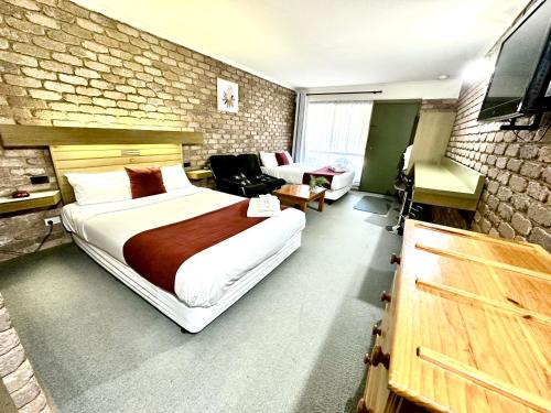 um quarto com uma cama grande e uma parede de tijolos em Eildon Lake Motel em Eildon