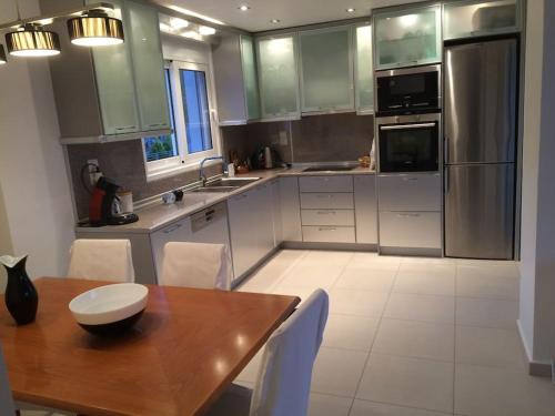 a kitchen with a wooden table and white appliances at Beautiful lux Villa Ilias Salamina in Salamís