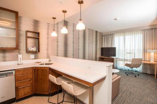 a kitchen with a sink and a desk with chairs at Residence Inn by Marriott Cincinnati Midtown/Rookwood in Cincinnati