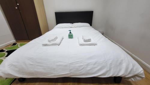 Una cama blanca con dos toallas y una botella. en Oleon en-suite Rooms - Ilford, London, en Ilford