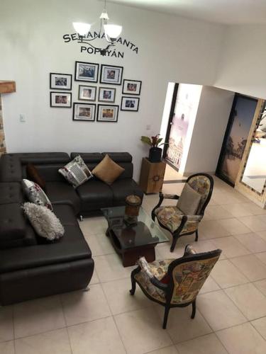 uma sala de estar com um sofá preto e cadeiras em Belen em Popayán