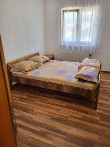 een bed in een slaapkamer met een raam en een houten vloer bij Vreshtat e Liqenit-Ezerski Llozja in Struga