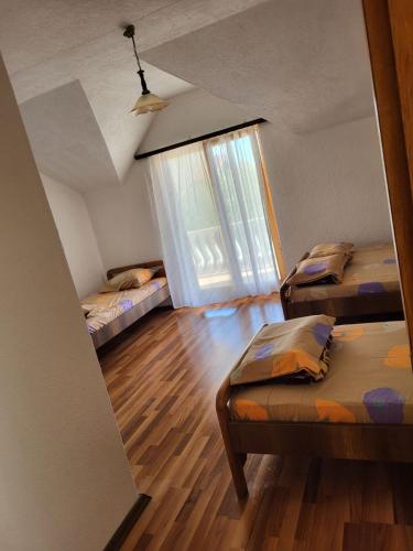 Cette chambre comprend 2 lits et une fenêtre. dans l'établissement Vreshtat e Liqenit-Ezerski Llozja, à Struga