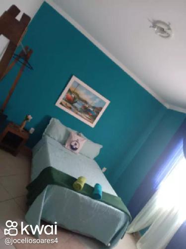 sypialnia z niebieskimi ścianami i łóżkiem z poduszkami w obiekcie Pousada pés na areia w mieście Serra
