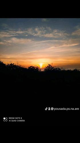una puesta de sol en un campo con el sol en el cielo en Pousada pés na areia en Serra
