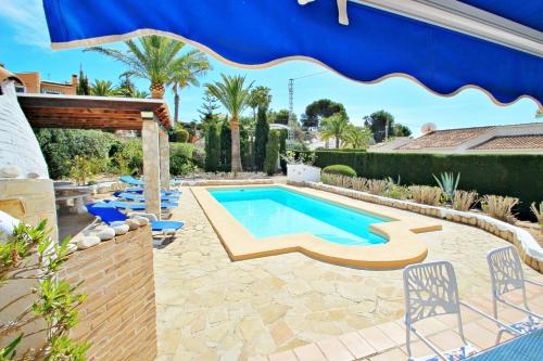 a swimming pool in a backyard with a blue umbrella at Kathrin - beautiful little house in pretty grounds with lovely views in Benissa in Benissa