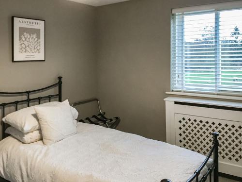 um quarto com uma cama com lençóis brancos e uma janela em Beck Cottage em Thirsk