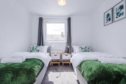 Stunning 3 br house near Leeds City Centre with Free Parking في Hunslet: سريرين في غرفة بها نافذة