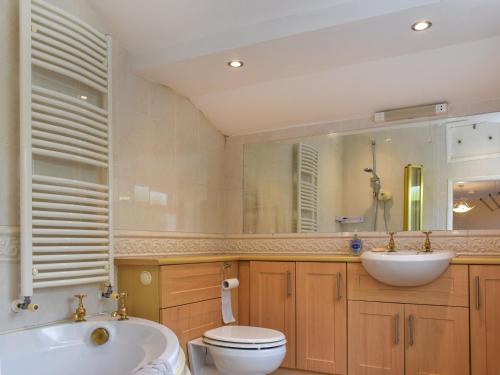 een badkamer met een wastafel, een toilet en een spiegel bij Waterside Cottage in Saltash