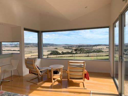 a room with a table and chairs and large windows at Lush Pastures in Bald Hills