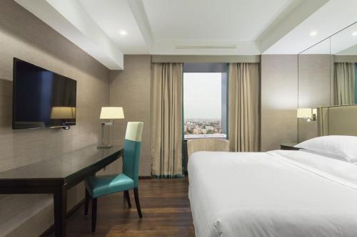 a hotel room with a bed and a desk and a bed and a window at Sheraton Bucharest Hotel in Bucharest