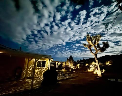 una palmera y un cielo nublado por la noche en Float Pool, Hot Tub, Sauna, Firepit, BBQ, Telescope, Views, EV Chg,, en Joshua Tree