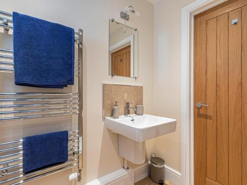 een badkamer met een wastafel, een spiegel en blauwe handdoeken bij The Old Stable in Dursley