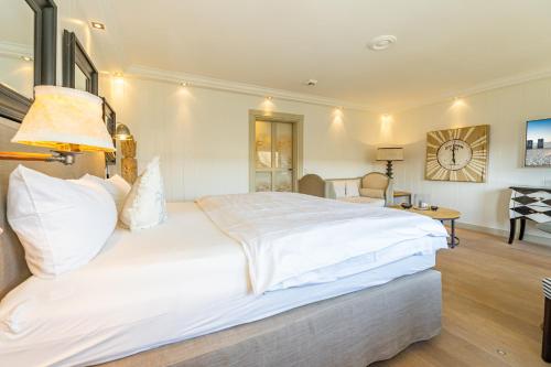 una camera da letto con un grande letto bianco con un orologio sul muro di Kampenkliff ehemals Walter´s Hof a Kampen