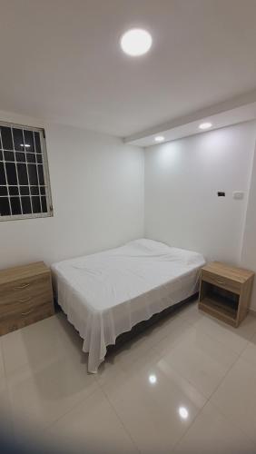 Habitación blanca con 1 cama y 2 mesas en Casa Villaconcha, en Valledupar