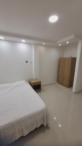 a white bedroom with a bed and a wooden cabinet at Casa Villaconcha in Valledupar