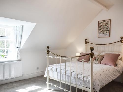 um quarto com uma cama branca e almofadas cor-de-rosa em Causeway Cottage em Wolsingham