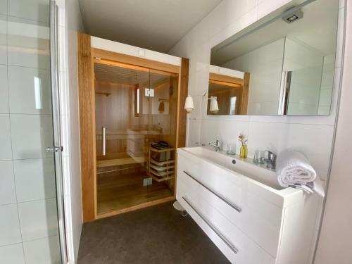 een badkamer met een witte wastafel en een douche bij Marina Strandbad Wellness-Chalet Romantik Haus Nr 411 in Olburgen