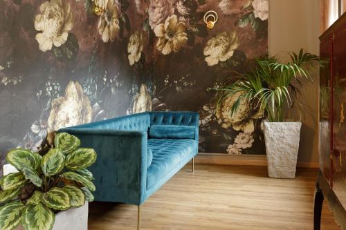 a blue couch in a room with plants at Domus 44 Rooms - Porta Nuova in Verona